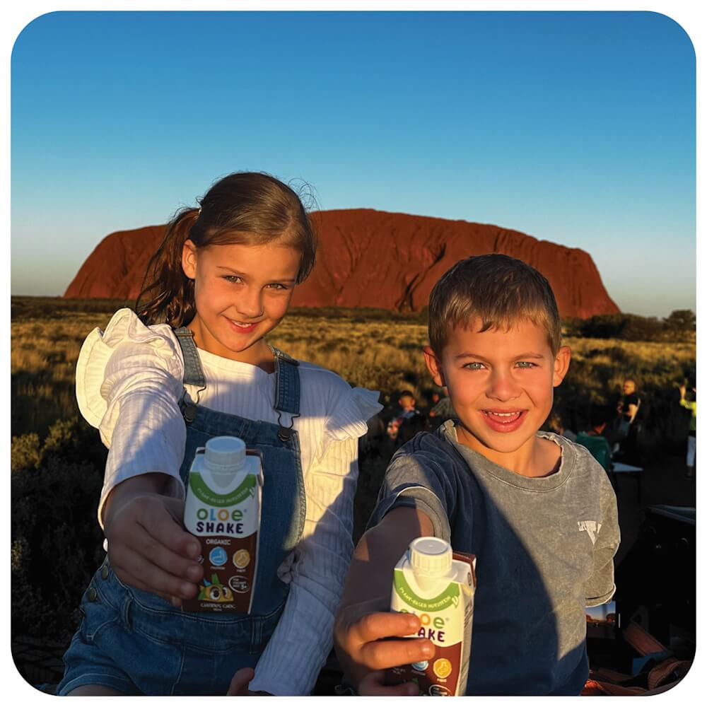 brother-and-sister-enjoying-their-chocolate-oloe-shakes-in-front-of-uluru